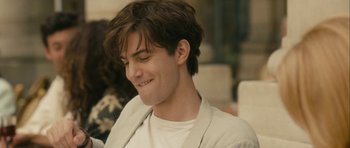 Movie still from “One Day” (2011), directed by Lone Scherfig – A young man with brown hair smiles at the camera; Close Up shot, Over the shoulder angle