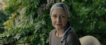 Movie still from “One Day” (2011), directed by Lone Scherfig – A woman wearing a head scarf standing in front of a bush; Close Up shot, Over the shoulder angle