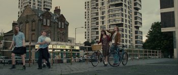 Movie still from “One Day” (2011), directed by Lone Scherfig – Two people standing next to each other on a sidewalk; Wide shot, Low angle