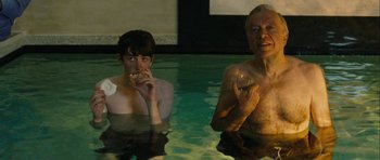Movie still from “One Day” (2011), directed by Lone Scherfig – A man and a woman in a swimming pool drinking wine; Medium shot, High angle