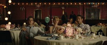 Movie still from “One Day” (2011), directed by Lone Scherfig – A group of people sitting at a table in a room; Medium shot, Over the shoulder angle
