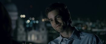 Movie still from “One Day” (2011), directed by Lone Scherfig – A young man is smiling for the camera in the dark; Close Up shot, Over the shoulder angle