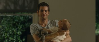 Movie still from “One Day” (2011), directed by Lone Scherfig – A man holding a baby in his arms and smiling; Close Up shot, Over the shoulder angle