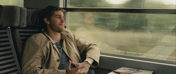 Movie still from “One Day” (2011), directed by Lone Scherfig – A man sitting on a train looking out the window; Medium shot, Over the shoulder angle