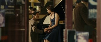 Movie still from “One Day” (2011), directed by Lone Scherfig – A man and a woman are shaking hands near a piano; Medium shot, Over the shoulder angle