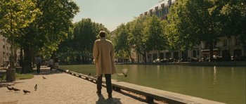 Movie still from “One Day” (2011), directed by Lone Scherfig – A man standing on the side of a road near a body of water; Extreme Wide shot, Over the shoulder angle