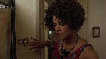Movie still from “One False Move” (1991), directed by Carl Franklin – A woman with curly hair is holding her hand up to a light switch; Close Up shot, Low angle