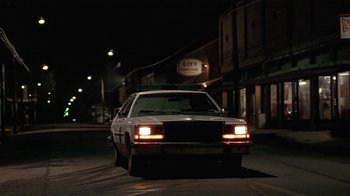 Movie still from “One False Move” (1991), directed by Carl Franklin – A car is parked on the side of the road at night; Wide shot, Low angle