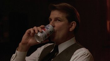 Movie still from “One False Move” (1991), directed by Carl Franklin – A man in a suit and tie drinking from a can; Close Up shot, Low angle