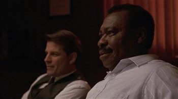 Movie still from “One False Move” (1991), directed by Carl Franklin – Two men sitting next to each other in front of a wall; Close Up shot, Low angle