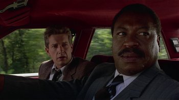Movie still from “One False Move” (1991), directed by Carl Franklin – Two men in suits in a red car looking at the camera; Close Up shot, Low angle