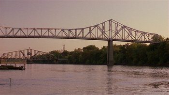 Movie still from “One False Move” (1991), directed by Carl Franklin – A bridge over a body of water near a forest; Extreme Wide shot, Low angle
