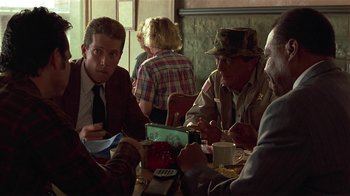 Movie still from “One False Move” (1991), directed by Carl Franklin – A group of people sitting at a table eating; Medium shot, Over the shoulder angle