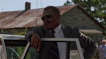 Movie still from “One False Move” (1991), directed by Carl Franklin – A man in a suit and sunglasses leaning on a railing; Close Up shot, Low angle