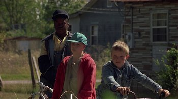 Movie still from “One False Move” (1991), directed by Carl Franklin – Three young people are standing next to a bicycle; Medium shot, Low angle