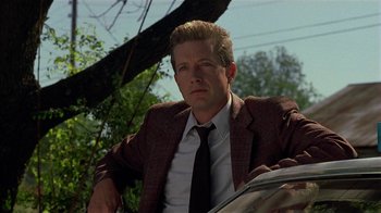 Movie still from “One False Move” (1991), directed by Carl Franklin – A man wearing a suit and tie holding a newspaper; Close Up shot, Low angle