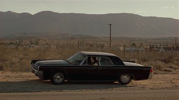Movie still from “One False Move” (1991), directed by Carl Franklin – A man sitting in the driver's seat of an old car; Extreme Wide shot, High angle