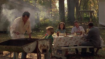 Movie still from “One False Move” (1991), directed by Carl Franklin – A group of people sitting at a table outside; Wide shot, High angle