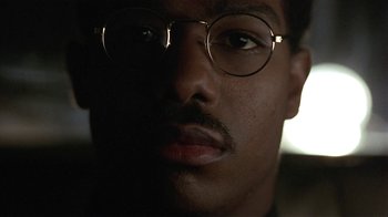 Movie still from “One False Move” (1991), directed by Carl Franklin – A person wearing glasses and a mustache; Close Up shot, Low angle