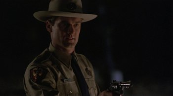 Movie still from “One False Move” (1991), directed by Carl Franklin – A man in a hat and uniform holding a gun; Close Up shot, Low angle