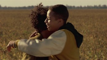 Movie still from “One False Move” (1991), directed by Carl Franklin – Two young people hugging in a field of brown grass; Close Up shot, Over the shoulder angle