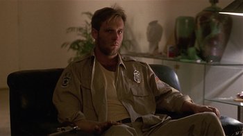 Movie still from “One False Move” (1991), directed by Carl Franklin – A man sitting on a couch in a living room; Close Up shot, Low angle