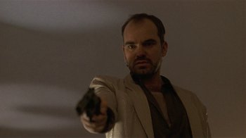 Movie still from “One False Move” (1991), directed by Carl Franklin – A man holding a gun in his right hand; Close Up shot, Low angle