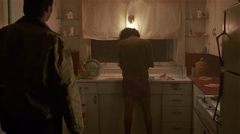 Movie still from “One False Move” (1991), directed by Carl Franklin – A person standing in a kitchen looking in a window; Medium shot, Over the shoulder angle