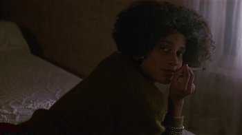 Movie still from “One False Move” (1991), directed by Carl Franklin – A woman sitting on a bed talking on a cell phone; Close Up shot, Over the shoulder angle