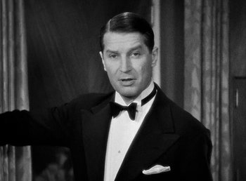 Movie still from “One Hour with You” (1932), directed by George Cukor – A man in a suit and bow tie; Close Up shot, Low angle