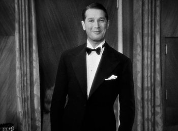 Movie still from “One Hour with You” (1932), directed by George Cukor – A man in a tuxedo standing in front of a curtain; Medium shot, Low angle