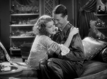 Movie still from “One Hour with You” (1932), directed by George Cukor – A man and a woman sitting on a couch; Medium shot, High angle