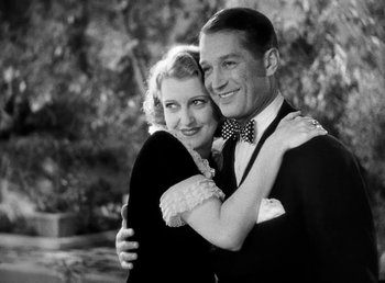 Movie still from “One Hour with You” (1932), directed by George Cukor – A man and a woman posing for a picture; Medium shot, Low angle