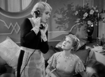 Movie still from “One Hour with You” (1932), directed by George Cukor – Two women are talking to each other while one is on the phone; Medium shot, High angle