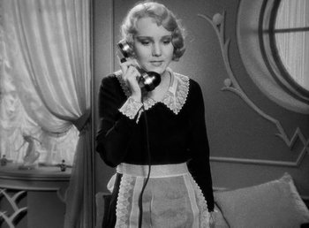 Movie still from “One Hour with You” (1932), directed by George Cukor – A woman holding a phone up to her ear while wearing an apron; Medium shot, High angle
