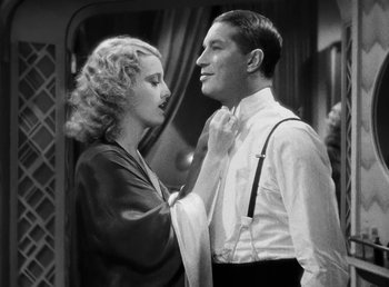 Movie still from “One Hour with You” (1932), directed by George Cukor – A man and a woman standing next to each other; Medium shot, Low angle