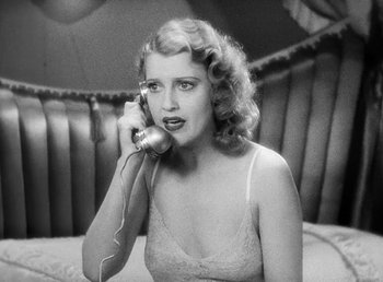 Movie still from “One Hour with You” (1932), directed by George Cukor – A woman is talking on a phone while sitting on a bed; Close Up shot, High angle