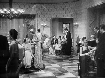Movie still from “One Hour with You” (1932), directed by George Cukor – A black and white photo of people sitting at tables in a room; Wide shot, High angle