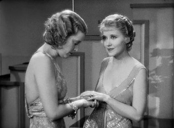 Movie still from “One Hour with You” (1932), directed by George Cukor – Two beautiful women looking at each other while holding a ring; Medium shot, High angle