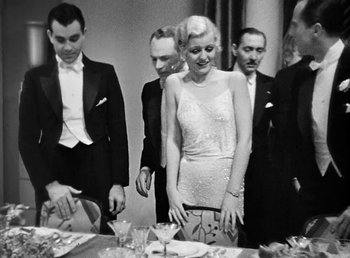 Movie still from “One Hour with You” (1932), directed by George Cukor – A group of people standing around a table with plates; Medium shot, Low angle