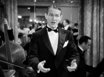 Movie still from “One Hour with You” (1932), directed by George Cukor – A black and white photo of a man in a tuxedo; Medium shot, High angle