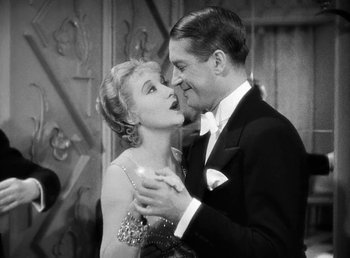 Movie still from “One Hour with You” (1932), directed by George Cukor – A man and a woman kissing each other in formal wear; Medium shot, Low angle