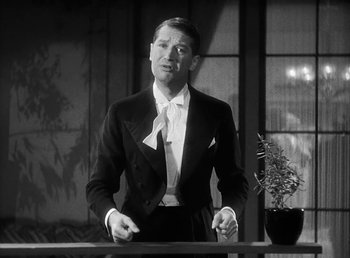 Movie still from “One Hour with You” (1932), directed by George Cukor – A black and white photo of a man in a suit and tie; Medium shot, Low angle