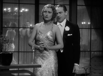 Movie still from “One Hour with You” (1932), directed by George Cukor – A man and a woman standing next to each other in formal wear; Medium shot, Low angle