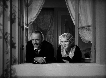 Movie still from “One Hour with You” (1932), directed by George Cukor – An older man and woman leaning against a window sill; Medium shot, Low angle
