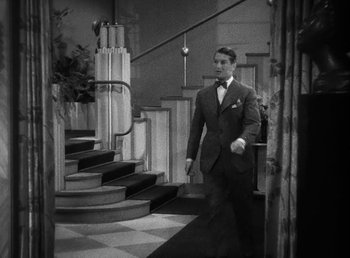 Movie still from “One Hour with You” (1932), directed by George Cukor – A black and white photo of a man in a suit walking down the stairs; Wide shot, High angle