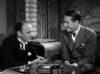 Movie still from “One Hour with You” (1932), directed by George Cukor – Two men sitting at a table talking to each other; Medium shot, Over the shoulder angle