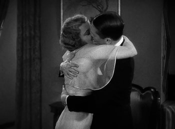 Movie still from “One Hour with You” (1932), directed by George Cukor – A man and a woman kissing each other in front of a mirror; Medium shot, Low angle