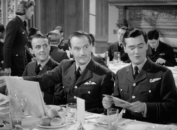 Movie still from “One of Our Aircraft Is Missing” (1942), directed by Emeric Pressburger – A black and white photo of three men sitting at a table; Medium shot, Low angle
