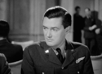 Movie still from “One of Our Aircraft Is Missing” (1942), directed by Emeric Pressburger – A man in a military uniform sitting in front of a crowd; Close Up shot, Low angle